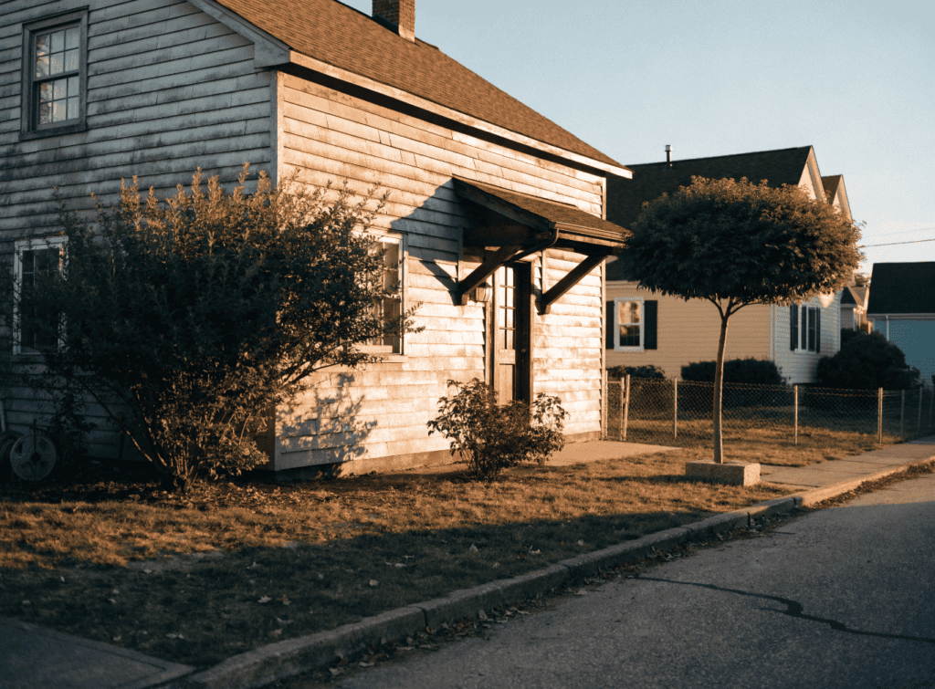 Golden Hour - Small Homes USA Newsletter Small house with wooden siding and trees in front, suburban neighborhood scene.