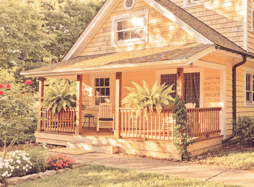 Charming Small Home with Front Porch - Small Homes USA Newsletter Cozy small house with a wooden porch and lush greenery.