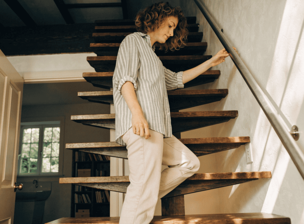Small Home Stairs - Small Homes USA Newsletter Woman descending wooden staircase in modern tiny home interior.