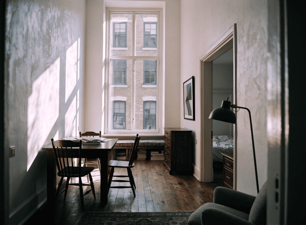 Taller Walls - Small Homes USA Newsletter Bright living room with large window, wooden floor, and minimal decor.
