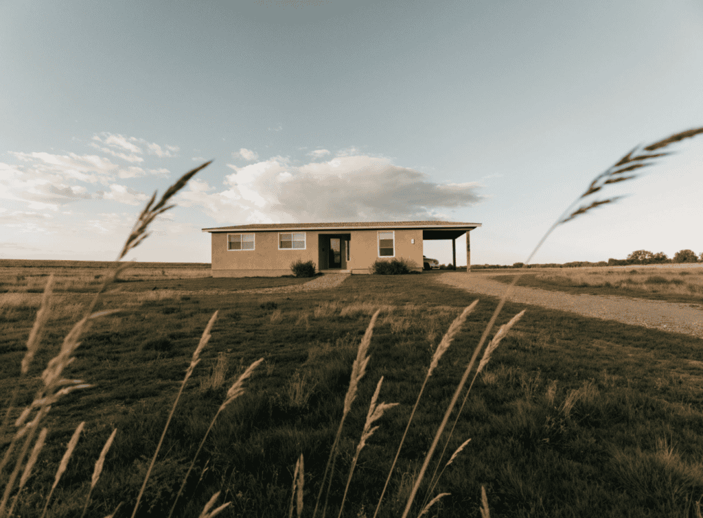 Tan Ranch Home - Small Homes USA Newsletter Small rural home with open landscape and clear sky in the background.